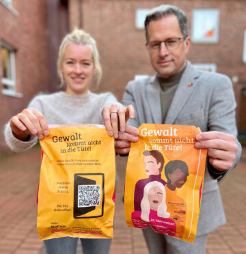 Zeigt die Gleichstellungsbeauftragte des Landkreises Stade, Elena Knoop, und Landrat Kai Seefried, die die Tüten vor sich halten.